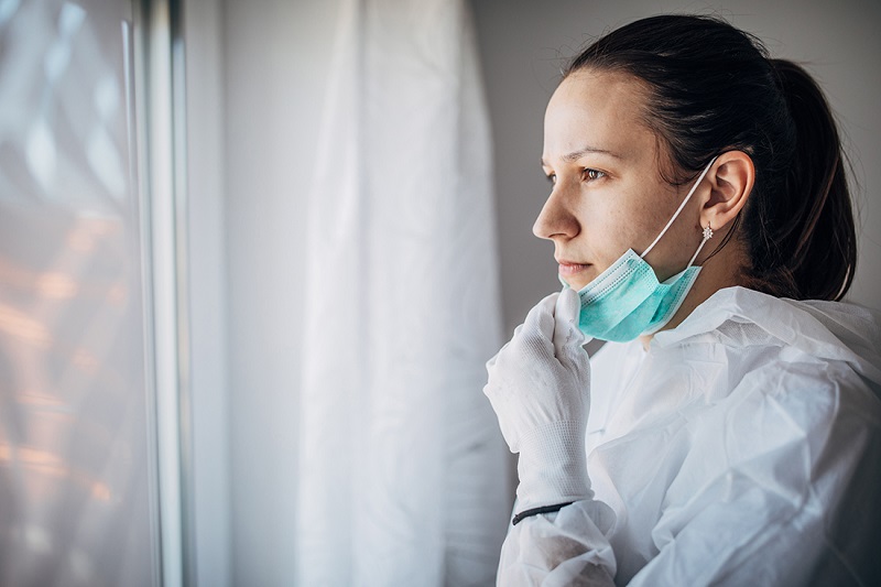 worried female doctor looking through the hospital window